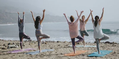 several people doing yoga in beach in bali